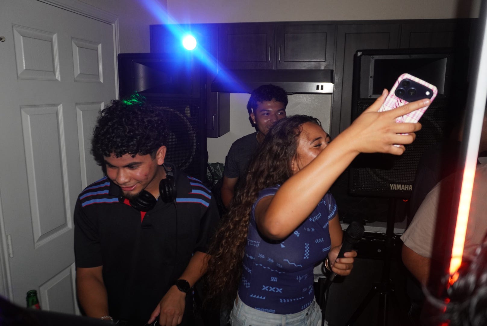 DJ Vinceanator at a house party with guests singing and colorful lights