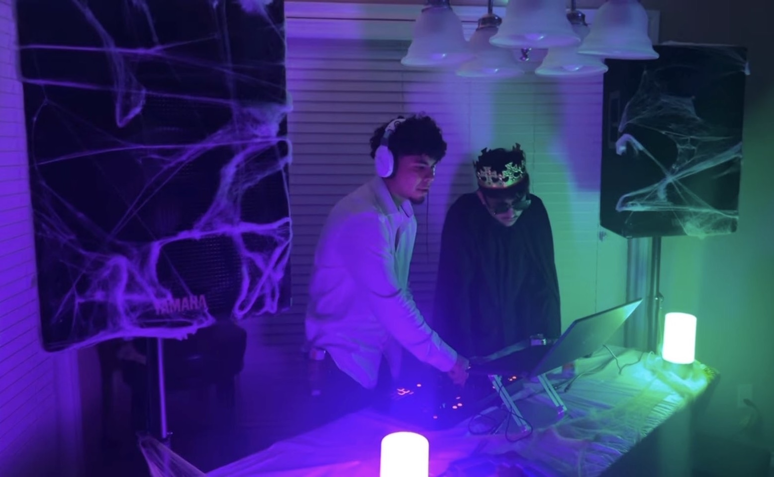 DJ Vinceanator and another DJ performing at a Halloween house party with purple and green lights